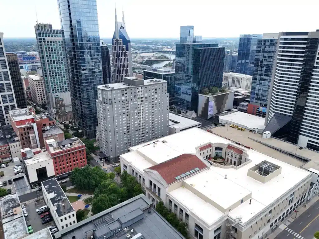 Aerial drone view of the Nashville Public Library's white flat membrane roof, a commercial roofing project completed by Southern Roofing Co., with the downtown Nashville skyline behind it